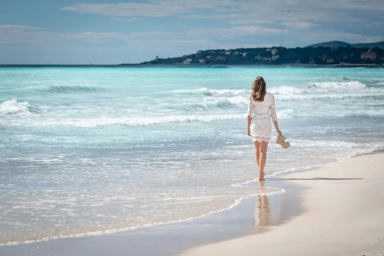 a woman on the beach walking with a bag