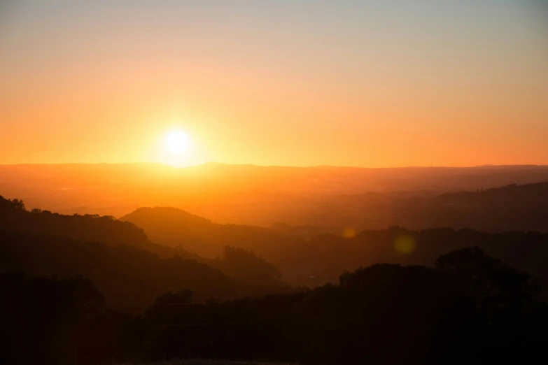 the sun is setting on the horizon in a mountain range