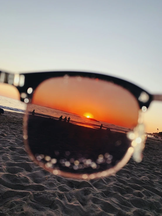 the sun sets over a beach and some sand