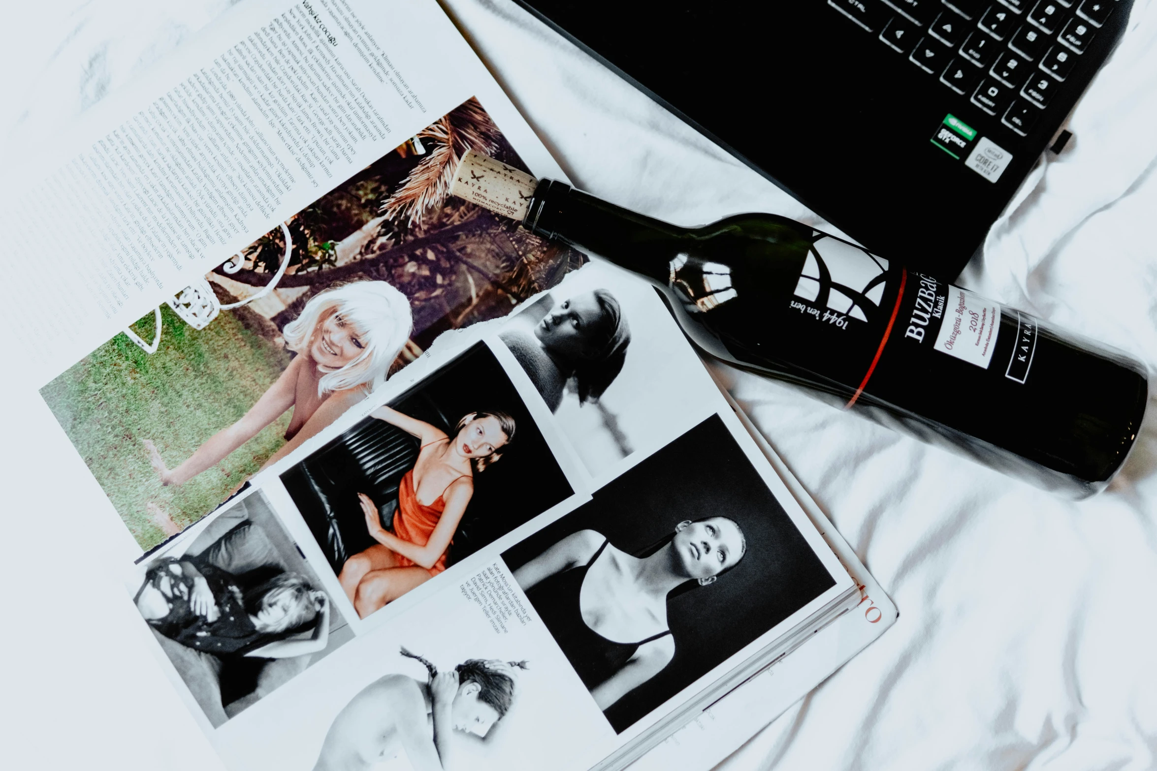 two books, a wine glass and an object are on a bed