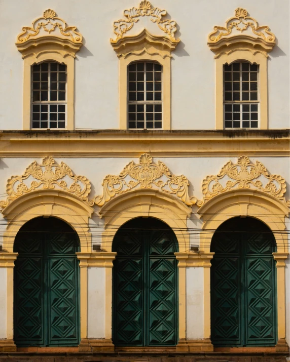 a tall building with three green doors and windows