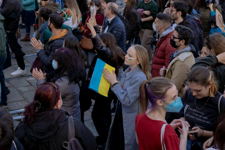 some people are standing on the sidewalk and one is holding up his hands