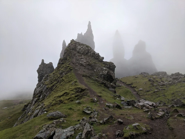 misty pograph of rocks and spires on grassy slope