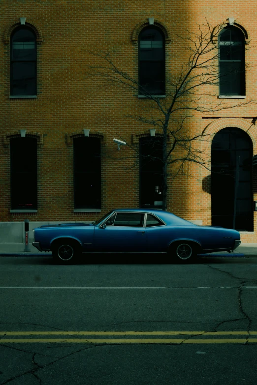 the car is parked in front of a tall building