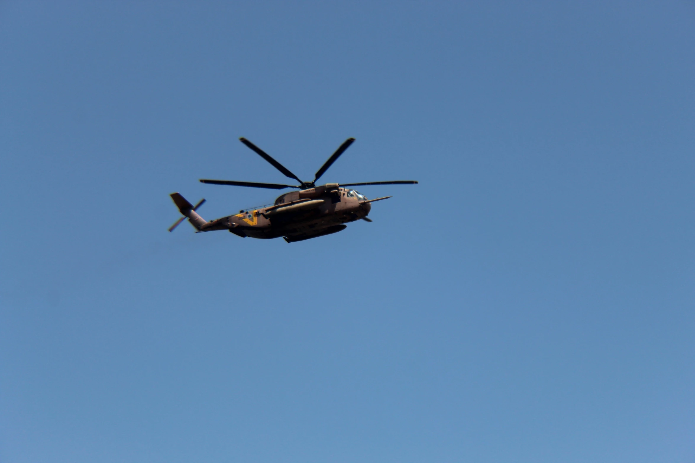 a small helicopter flying through the air with landing gear down