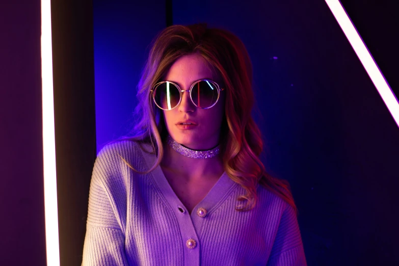 a blonde woman in purple clothing wearing sunglasses and looking down at soing