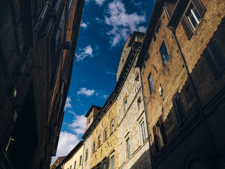 a street filled with tall buildings under a blue cloudy sky