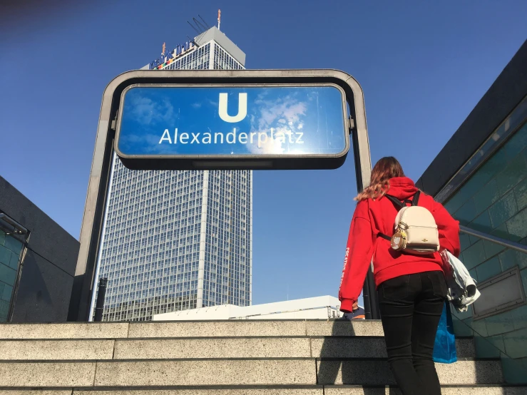 a young woman is walking down stairs next to a sign that says alexandentuts