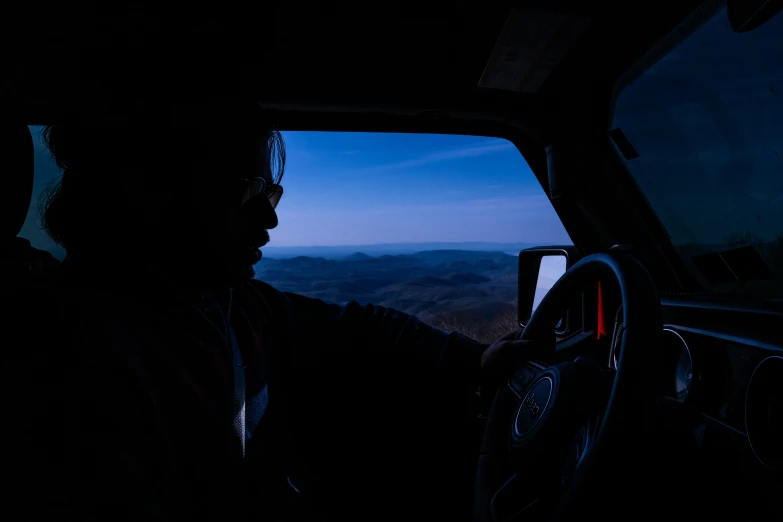 a man sitting in a truck at night looking out a window