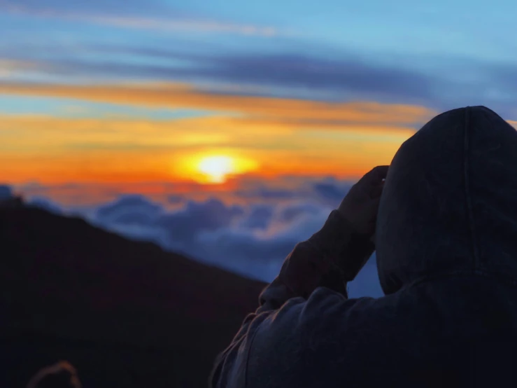 the sun rising above the clouds over a mountain range