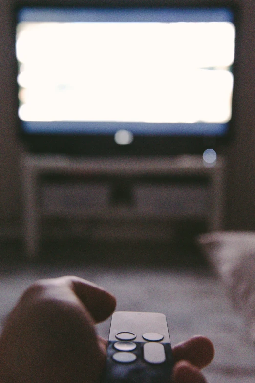 someone holding a remote control in front of a flat screen television