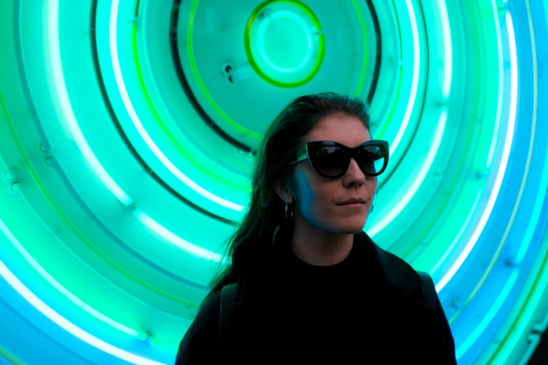 a woman with dark glasses and green lights behind her