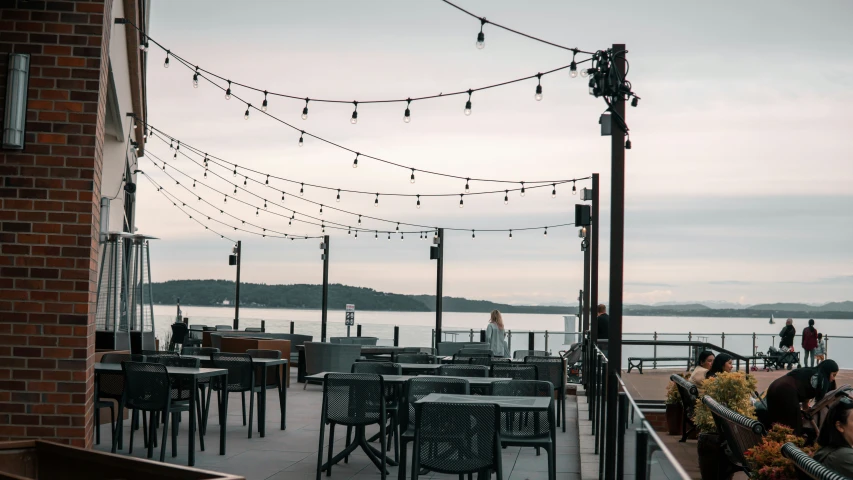 empty chairs and tables at an outdoor eatery next to a harbor