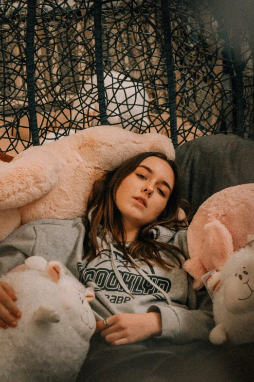 a girl lying down in bed with two large stuffed animals