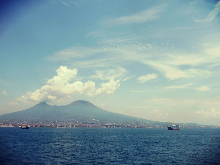 boat near shore and mountain in distance under clouds