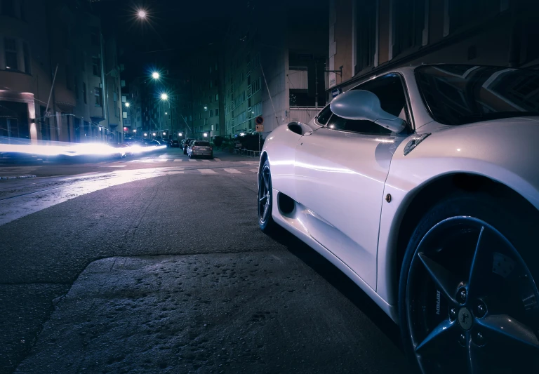 a white sports car on a street at night time