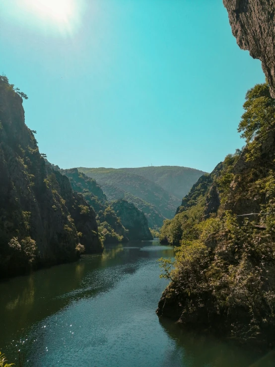 a river flows through the mountains on a sunny day