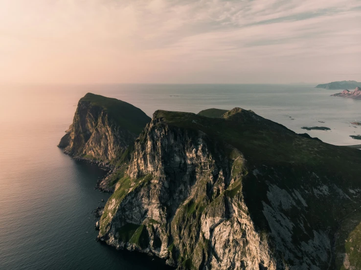 an aerial s of some green mountains with the ocean and sky in the background