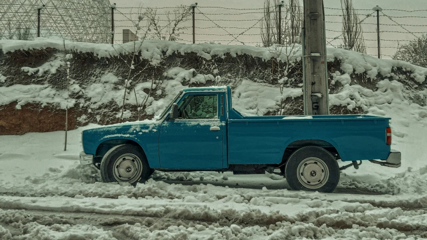 a blue pick up truck on a snowy street