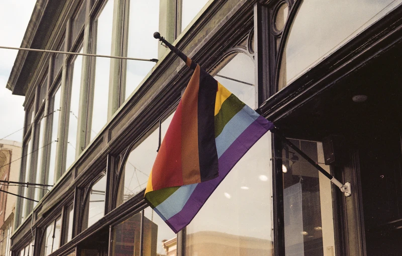 a rainbow flag on a window in front of an old building