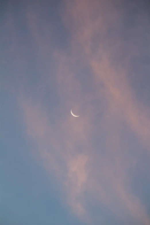 the moon is in the sky with pink clouds