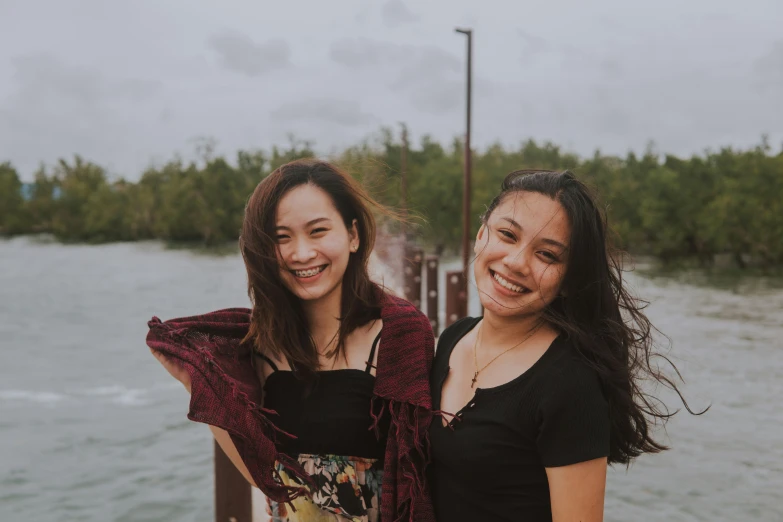 two young women posing for the camera near a lake