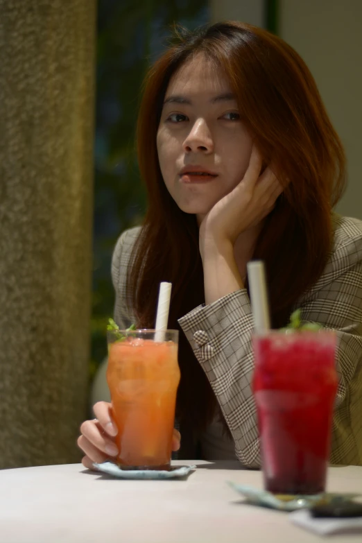 a woman sitting at a table with two drinks