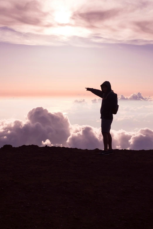 a person on top of a hill pointing at the sky