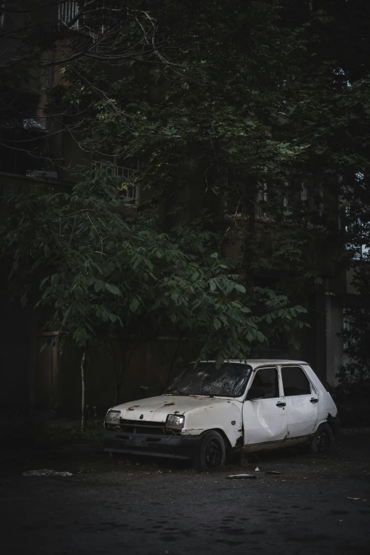 a white car with burnt out front parked on the side of a road