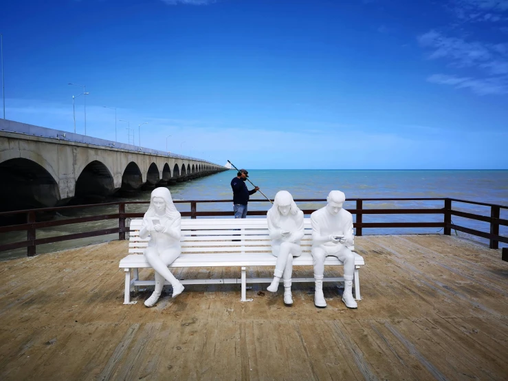 some people are sitting on a bench near the water