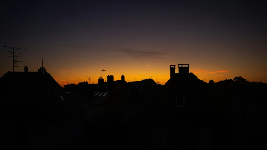 an orange sunset over a city with dark buildings