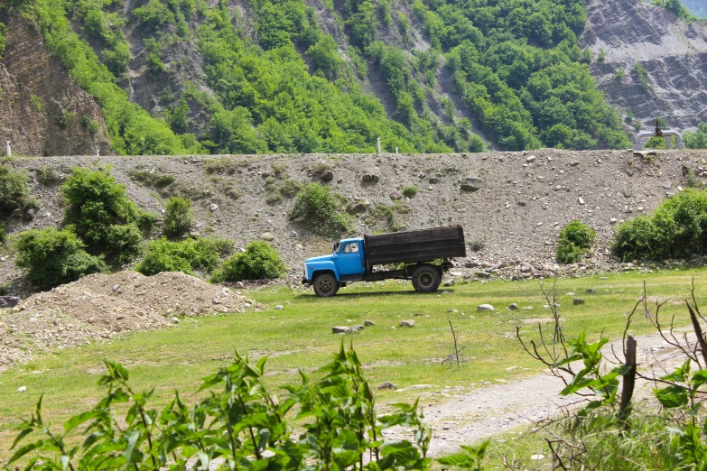 a blue truck sitting in the middle of a field