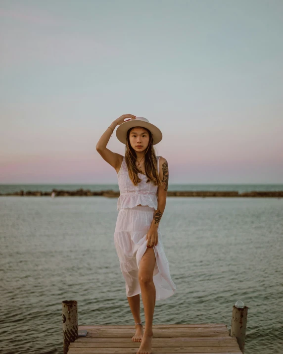 a beautiful young woman in a hat on a pier