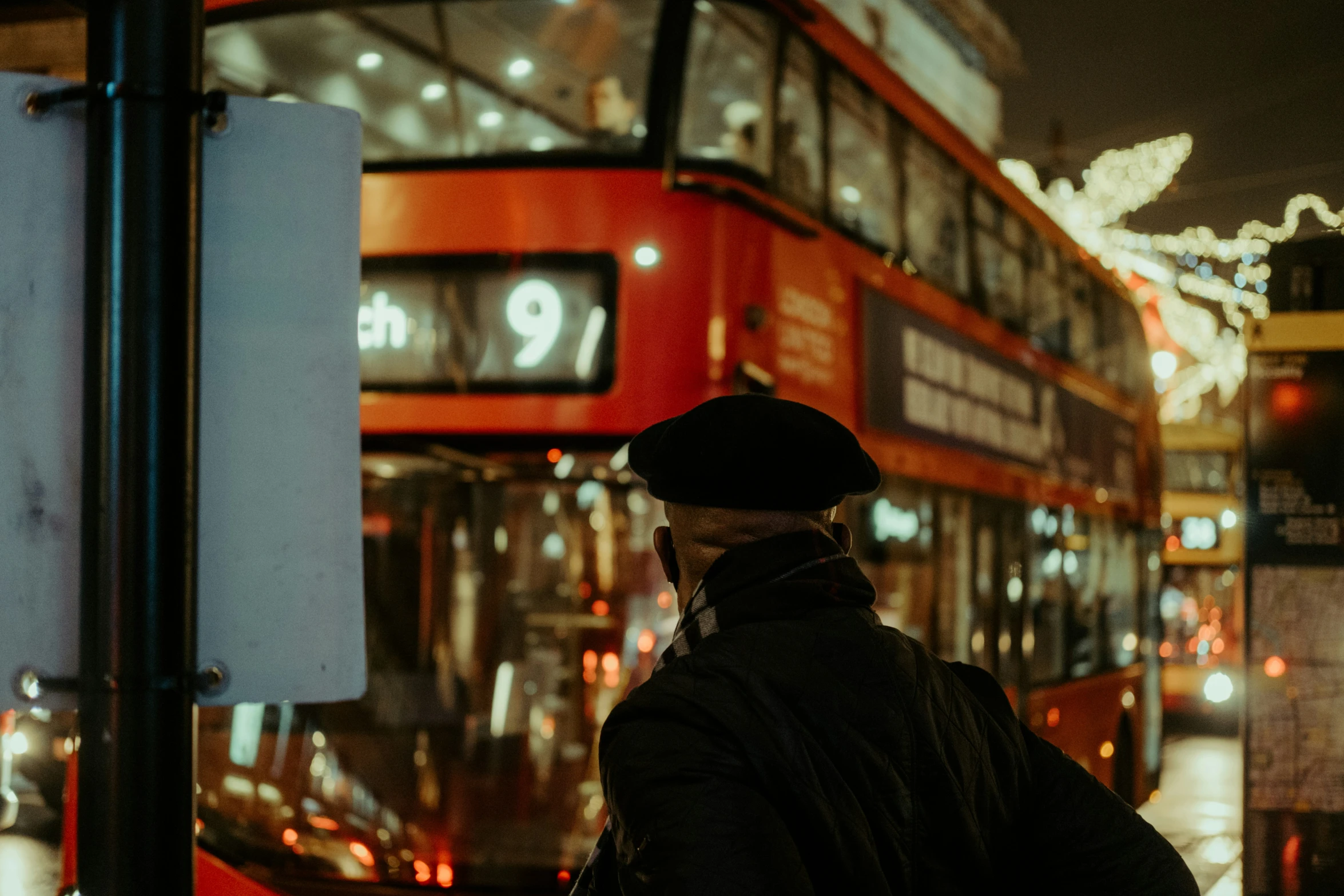 a man standing on the sidewalk near a double decker bus