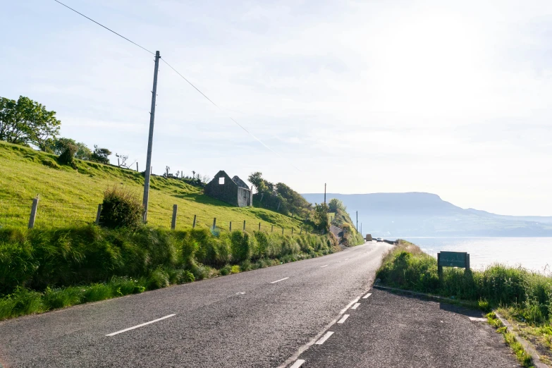 a car driving on a winding road with grass and the water in the background