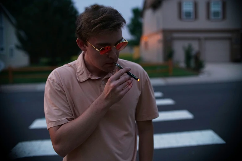 a man in sunglasses smoking a cigarette on a street