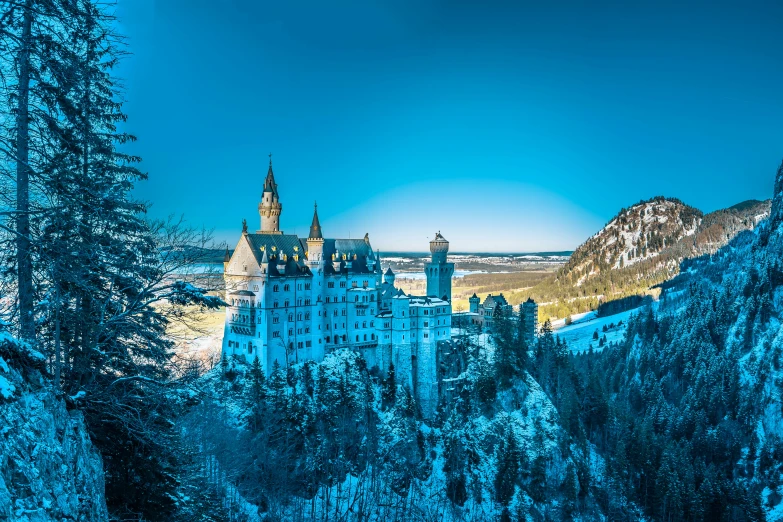 a castle sits at the base of a tree covered hill