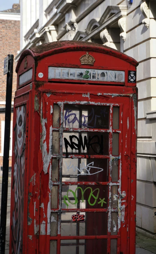 a telephone booth covered in graffiti and writing