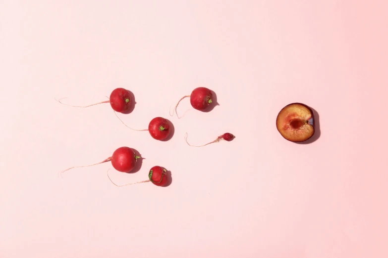 four cherrys and two other objects on a pink surface