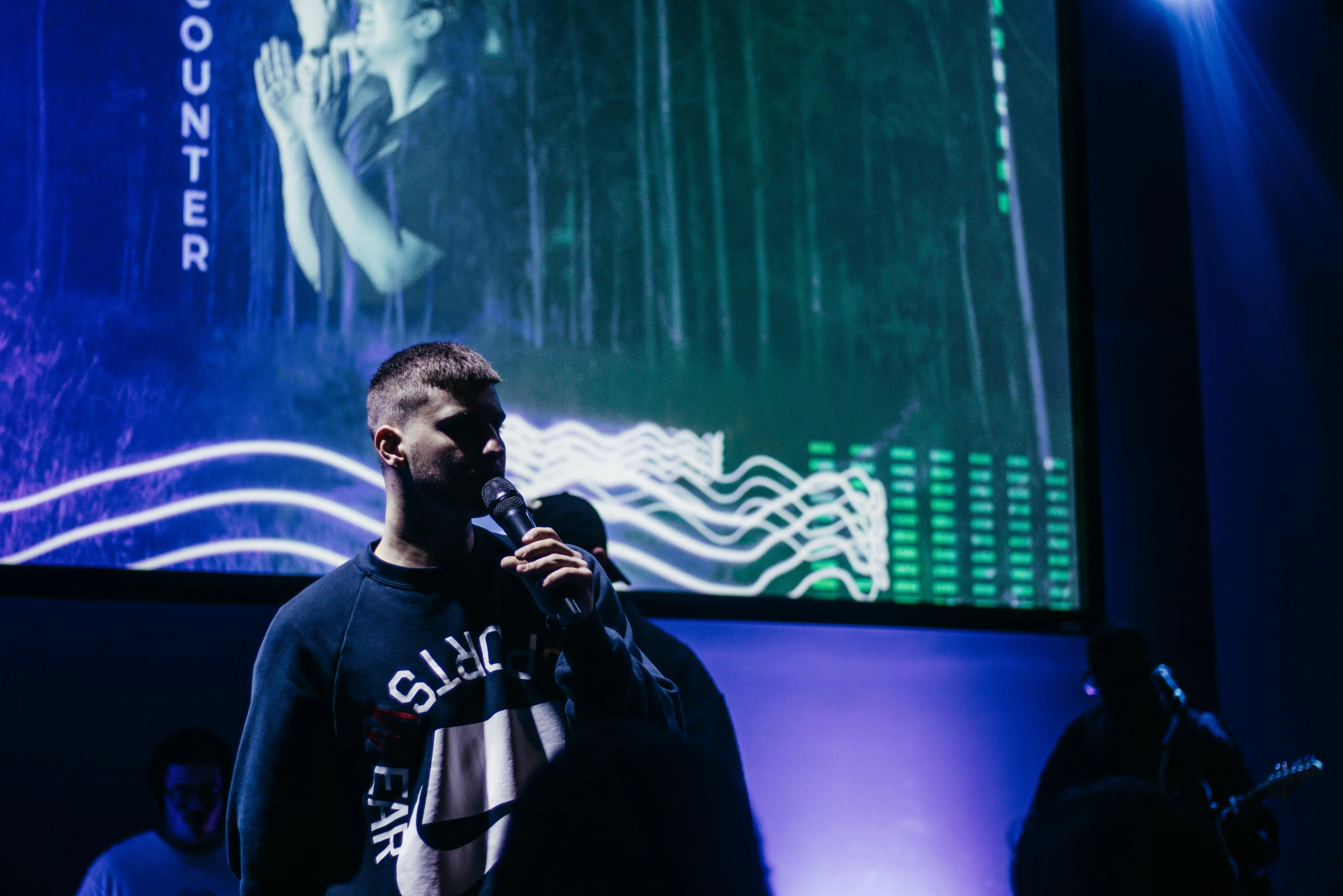 a man holding a microphone standing in front of a projection