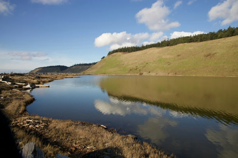 a small body of water with trees on the hill