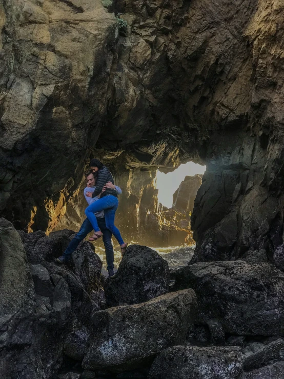 two people taking a selfie with a cave in the background