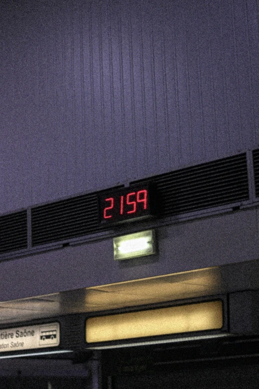 a clock mounted to the side of a building at night