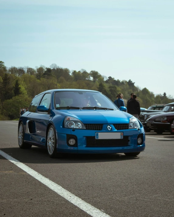 a blue car driving down a street next to a forest