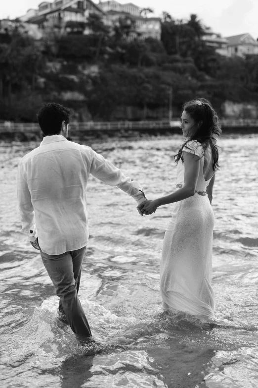 the couple are walking through the water with their hands together