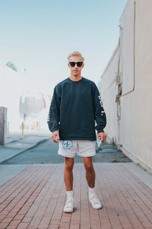 a young man wearing sunglasses, a black sweatshirt and white shorts