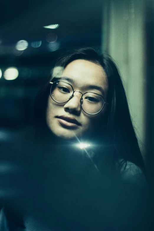 a woman wearing glasses sitting in front of a camera