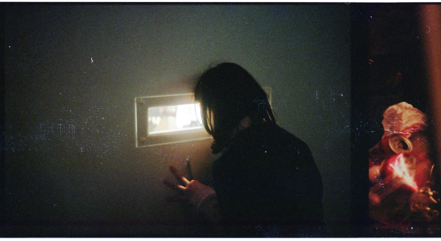 a man in a dimly lit dark room with the light from behind him