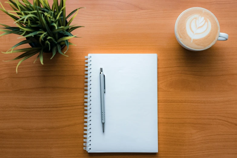 a cup of coffee next to a small notebook and pen