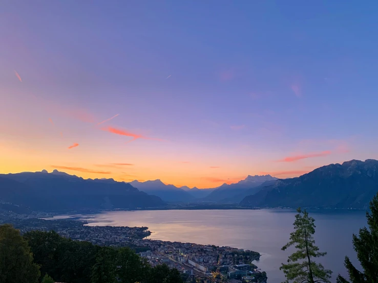 an ocean view of a city and mountains at sunset